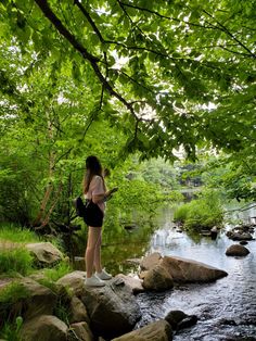 a woman standing on rocks in front of a river