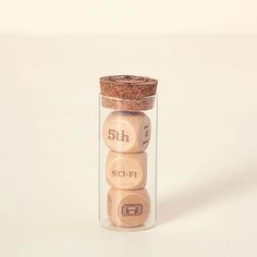 three wooden dices in a glass jar on a white surface with a cork top