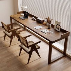 a wooden table with two chairs next to it and a laptop on top of it