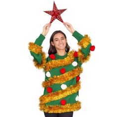 a woman in a christmas sweater holds up a star above her head while standing against a white background