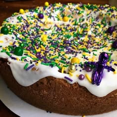 a cake with white frosting and sprinkles on it sitting on a plate