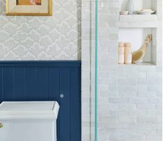 a white toilet sitting in a bathroom next to a blue tiled wall with shelves above it