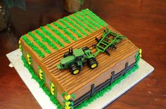 there is a cake that looks like a farm house with tractors on it and green grass