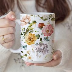 a woman holding a coffee mug with flowers on it