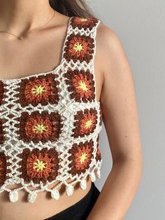 a close up of a woman wearing a crocheted top with flowers on it