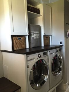 a washer and dryer in a laundry room next to cabinets with baskets on them