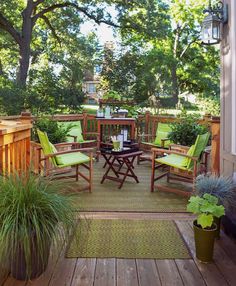 an outdoor patio with green chairs and plants on the deck, surrounded by greenery