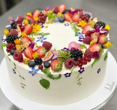 a white cake topped with fresh fruit and flowers