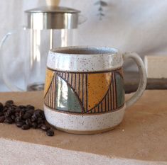 a coffee cup sitting on top of a counter next to beans