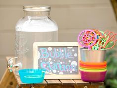 a table topped with cups and bowls next to a mason jar filled with magnets