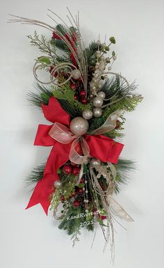 a christmas wreath hanging on the wall with ornaments and greenery around it's edges