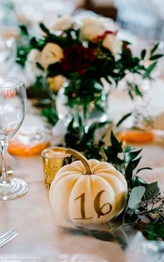 the table is set with white pumpkins and greenery for an elegant fall wedding