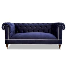 a blue velvet couch with gold trimmings and buttons on the arm, sitting in front of a white background