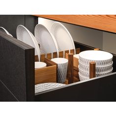 several white plates and cups are in a black drawer under a wooden countertop,