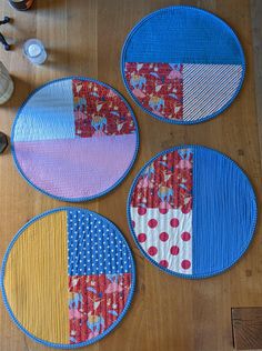 three circular quilted placemats sitting on top of a wooden floor next to a pair of shoes