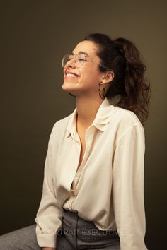 a woman wearing glasses sitting down and smiling at the same time as she looks up