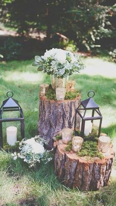 an arrangement of candles, flowers and moss on a tree stump in the middle of a yard