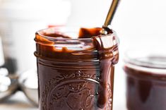 a jar filled with chocolate pudding sitting on top of a counter next to spoons