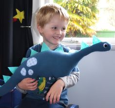 a young boy sitting in a chair holding a stuffed animal