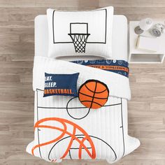 a basketball themed comforter and pillow set on a bed with wood flooring in the background