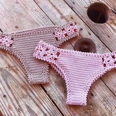 two pink crocheted bikinis sitting on top of a wooden floor next to donut