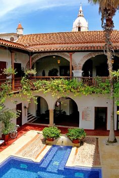 an outdoor swimming pool in the middle of a courtyard with potted plants on either side