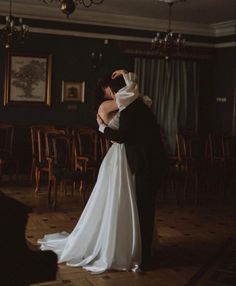 a bride and groom dance together in an old - fashioned room with chandeliers