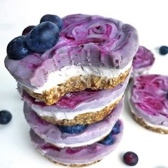 blueberry cheesecakes stacked on top of each other with frosting and berries