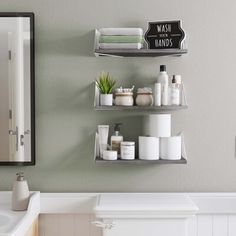 bathroom shelves with various items on them in front of a mirror and sink under a sign that says wash hands