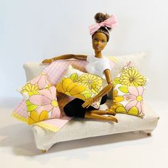 a doll sitting on top of a couch with pillows in it's back legs