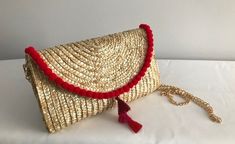 "From an evening cocktail party to a fun beach day, this straw clutch makes a graceful accessory to carry. Perfect for a summer statement. Red pom poms with red/pink tassel center.  Comes w/ removable gold chain strap that can be worn as a crossbody or shoulder strap. NOTE:  Pom pom embellishment is only on the top fold of the clutch (NOT on the back or other edges of the clutch) Details: Clutch Size: 6.5\" x 10\" Shoulder strap: 47\" gold Face material: wheat straw Lining material: polyester and cotton" Gold Straw Bag For Summer Evenings, Chic Clutch With Tassels, Gold Straw Evening Bag For Summer, Summer Evening Straw Bag, Bohemian Summer Evening Clutch, Summer Evening Clutch Straw Bag, Summer Evening Straw Clutch Bag, Evening Summer Clutch Straw Bag, Chic Red Woven Straw Bag