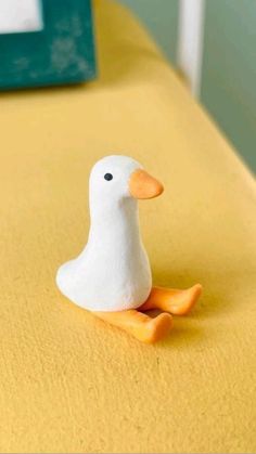 a small white duck sitting on top of a bed