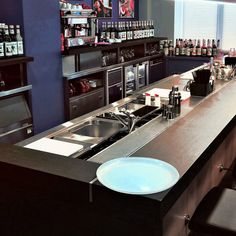 an empty bar with several bottles on the shelves and a sink in front of it