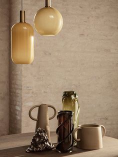 three lamps hanging over a table with coffee cups and vases