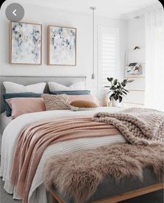 a bed with blankets and pillows on top of it next to two pictures above the bed