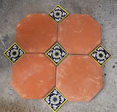 four orange and blue tiles arranged on the ground with an intricate design in between them