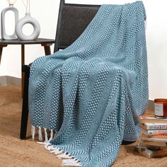 a blue and white blanket sitting on top of a chair next to a book shelf