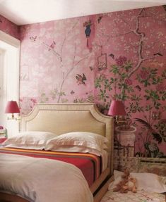 a bed room with a neatly made bed next to a window and a pink wallpaper