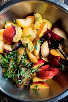 a metal bowl filled with fruit and greens