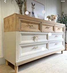 a white dresser with drawers and flowers on top