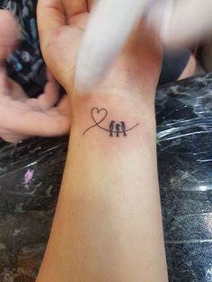 two birds sitting on a branch with a heart tattoo