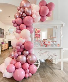 the balloon column is decorated with pink, white and silver balloons for an elegant birthday party