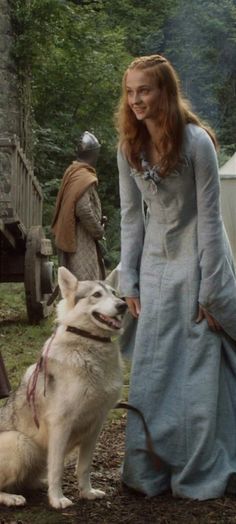 a woman standing next to a white dog