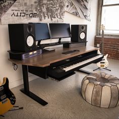 a computer desk with two monitors and a keyboard on top of it next to a stool