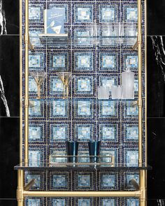 a glass shelf in front of a black wall with blue and white tiles on it