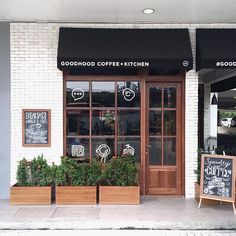 the outside of a coffee shop with wooden planters and chalkboards on the windows