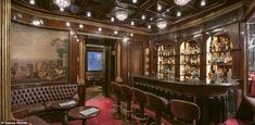 a fancy bar with leather chairs and paintings on the wall behind it, along with red carpeted flooring