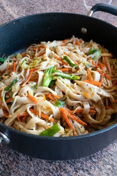 a pan filled with noodles and vegetables on top of a table