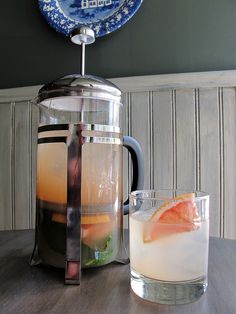 a pitcher and glass sitting on top of a wooden table next to a blue plate