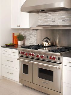 a stove top oven sitting inside of a kitchen next to white cabinets and counter tops